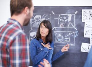 Getting her ideas across. Shot of two coworkers planning a storyboard on a blackboard.