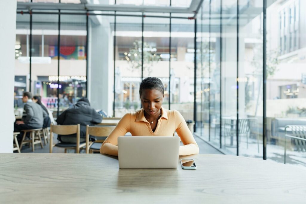 Young african woman freelancer working on laptop while sitting in coworking